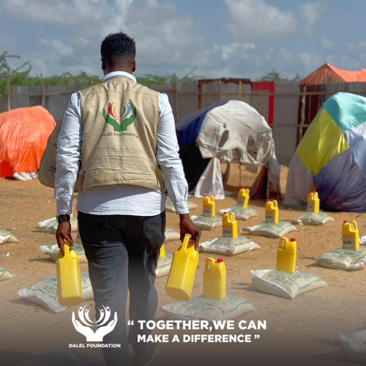 Dalel Foundation field worker carrying cooking oil past rows of rice sacks laid out beside family shelters